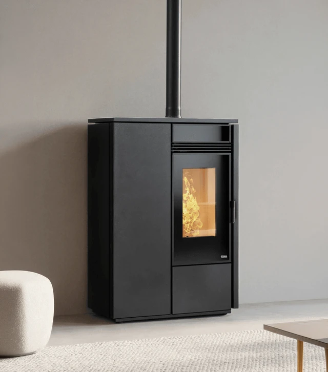 Intérieur moderne avec poêle à granulés cylindrique noir en fonctionnement, flammes orange vives visibles derrière vitre panoramique